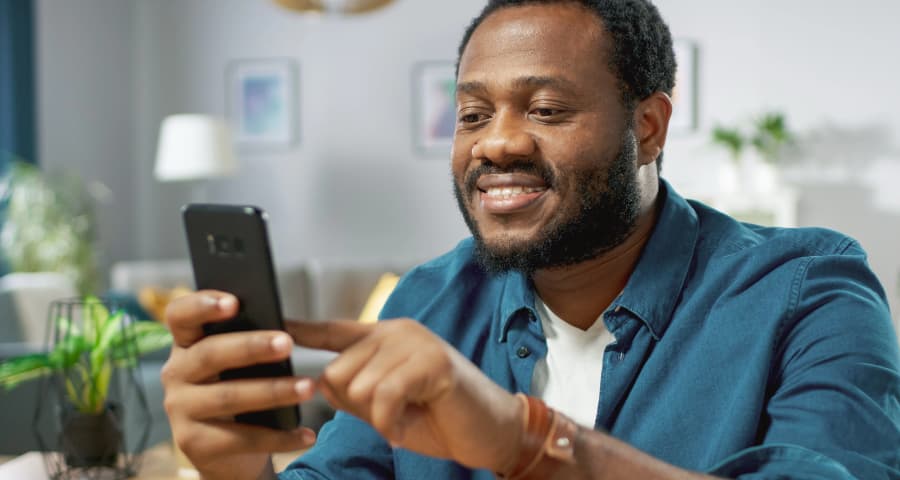 Man in his home interacting with a home security app on his cell phone